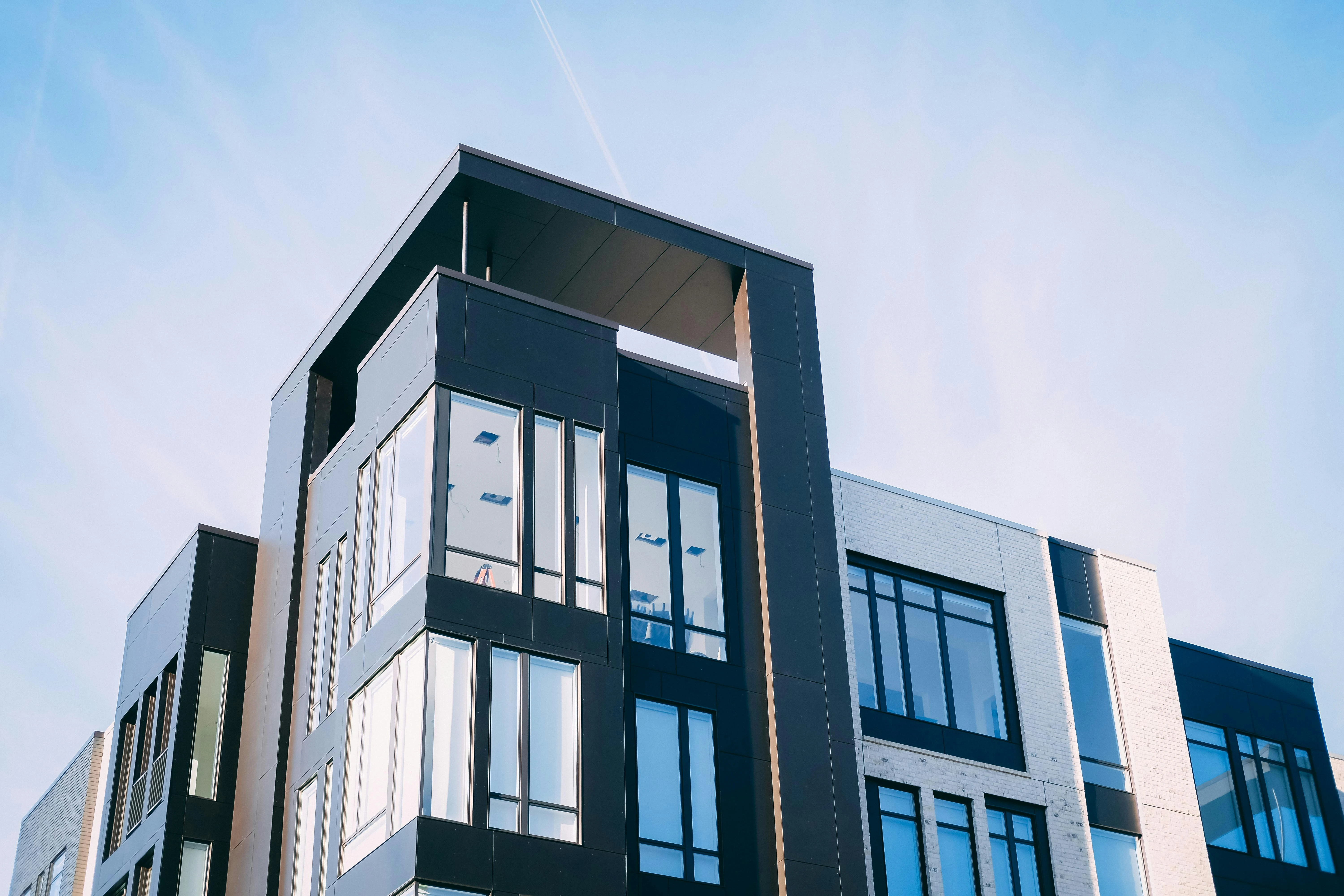 Modernes Wohngebäude mit dunkler Fassade und großen Fenstern unter blauem Himmel